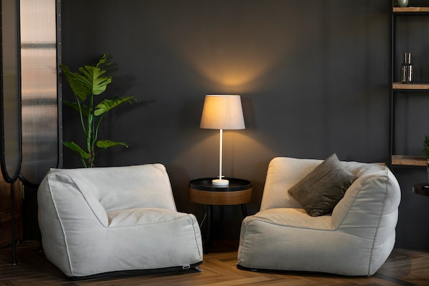 Два современных белых кресла-мешка с небольшим круглым столиком и лампой между ними в уютной, тускло освещенной комнате.
